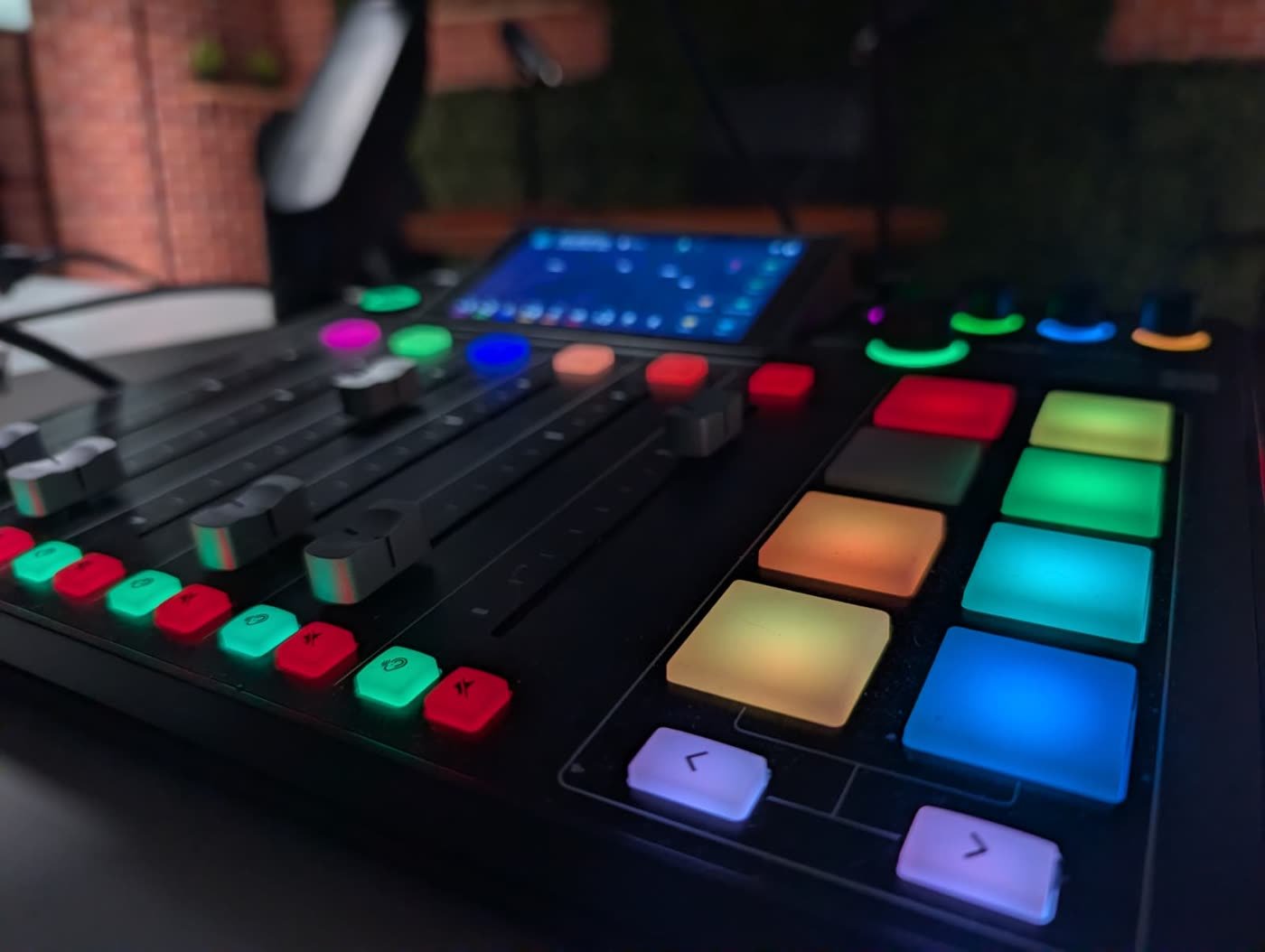 Close-up of a professional audio and lighting control board with illuminated channel faders and pads